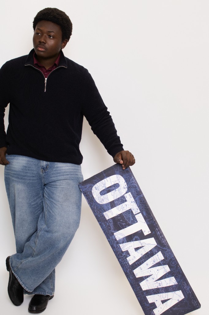 Rayann Sagnon holding an Ottawa sign in a studio portrait.